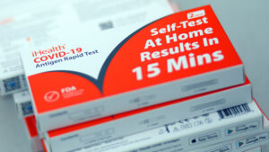 A collection of the self test kit for covid 19 with white and red package. The set of the tests packages are vertically bundled on top of each other