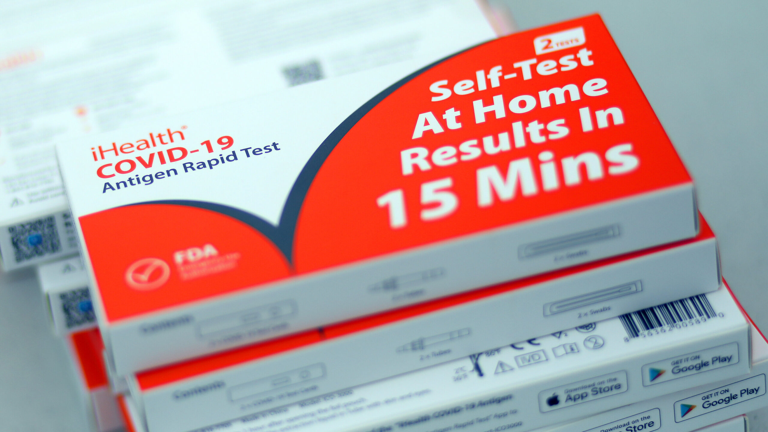 A collection of the self test kit for covid 19 with white and red package. The set of the tests packages are vertically bundled on top of each other